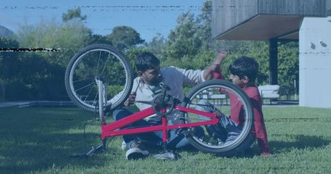 Father and son repairing red bicycle on lawn teaching bike maintenance and outdoor bonding