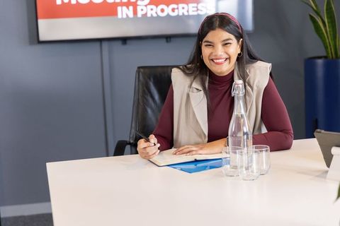 Smiling businesswoman taking notes during boardroom meeting in modern office