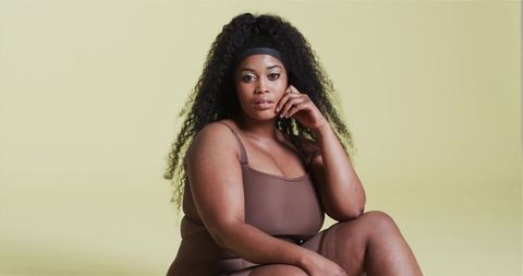 Confident Woman Posing against Yellow Background in Brown Apparel