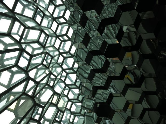 Interior detail capturing abstract hexagonal glass and metal structure with geometric shapes and reflections. Can be used for architectural design, modern construction, and symmetry-focused creative projects.