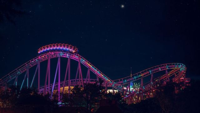 Neon-lit roller coaster against starry night sky