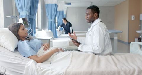 Doctor Consulting Patient in Hospital Room Using Tablet