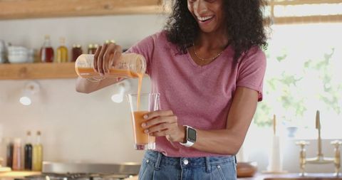 African American Woman Enjoying Fresh Smoothie in Modern Kitchen