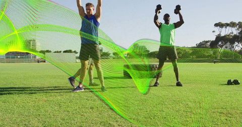 Group performing overhead dumbbell presses on grass field with dynamic green wave overlay