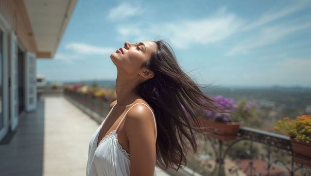 Sunlit terrace portrait of woman basking in breeze with flowing hair and floral planters