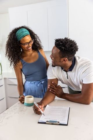 African american couple signing agreement at bright modern kitchen island, smiling