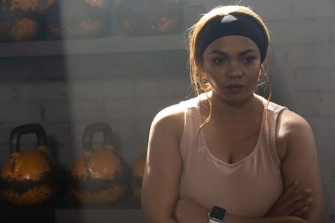 Hispanic woman resting after kettlebell workout showing focus and determination in gym