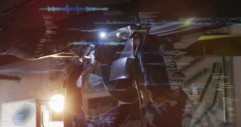 Female auto technician welding under vehicle with augmented reality hud and protective gear