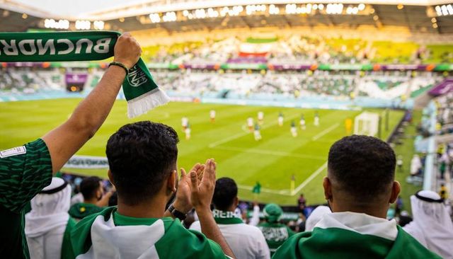 Passionate football fans cheering in stadium wearing green and white scarves and robes