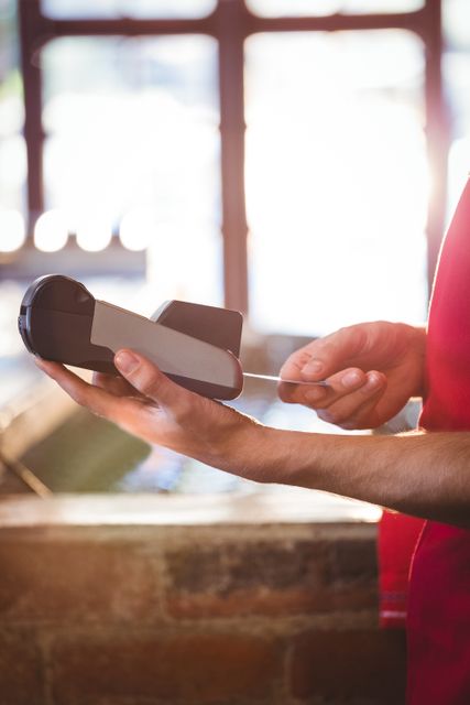 Mid section of waiter inserting customer's credit card into credit card machine