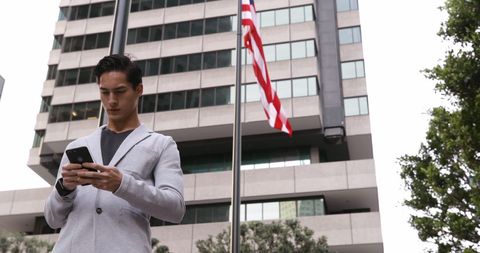 Confident businessman focused on smartphone outdoors cityscape