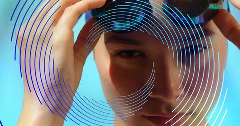 Sunlit swimmer adjusting goggles with circular graphic overlay, close-up portrait