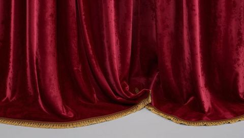 Luxurious crimson velvet theater curtains with gold fringe and pooled folds