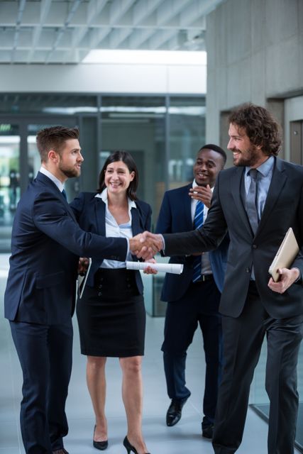 Businesspeople shaking hands in a modern office environment, symbolizing successful collaboration and partnership. Ideal for use in business-related content, corporate websites, presentations, and marketing materials to convey professionalism, teamwork, and successful business relationships.