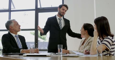 Confident Businessman Presenting to Colleagues in Modern Office