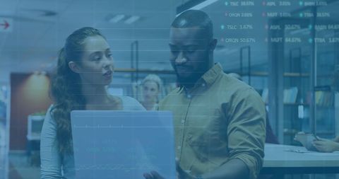 Diverse team analysing financial data on digital tablet in modern office