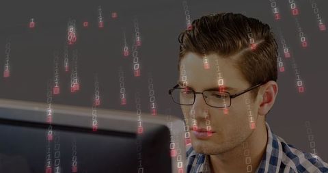 Young developer analyzing binary code on monitor wearing glasses and plaid shirt