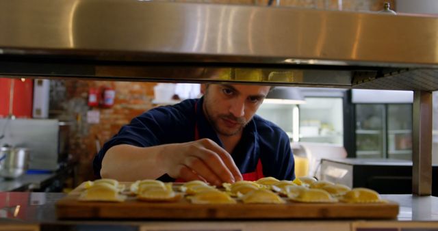 Focused biracial cook making dumplings in restaurant kitchen. Cooking, profession, food, work and lifestyle, unaltered.