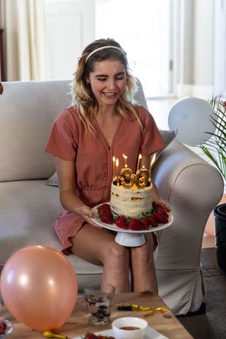Woman turning 30 holding birthday cake in cozy home setting