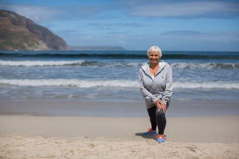 Senior woman practicing lunges on beach embracing healthy lifestyle outdoors
