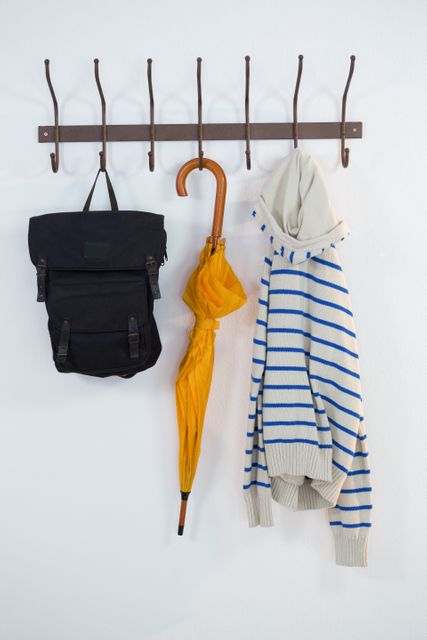 Close-up of hoodie, umbrella and bag hanging on hook