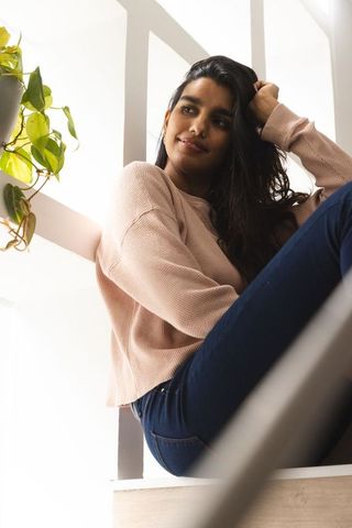 Stylish woman relaxing on minimalist staircase next to vine