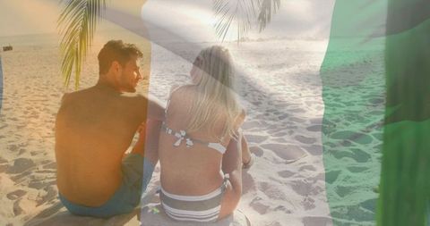 Couple relaxing on sandy beach at sunset with palm frond, ocean horizon and green overlay