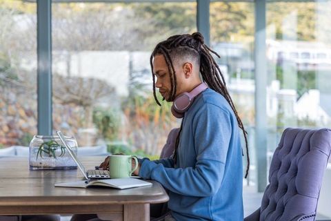 African american man working on laptop with mug and headphones in modern workspace
