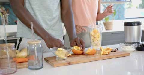 Couple Preparing Fresh Fruit Smoothies in Kitchen