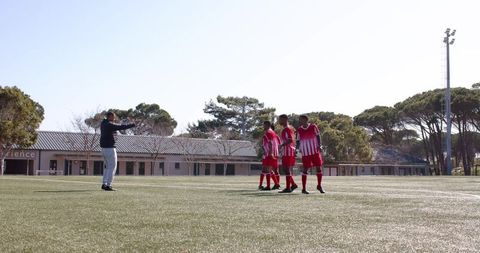 Youth soccer team practicing drills on sunny field demonstrating team coordination