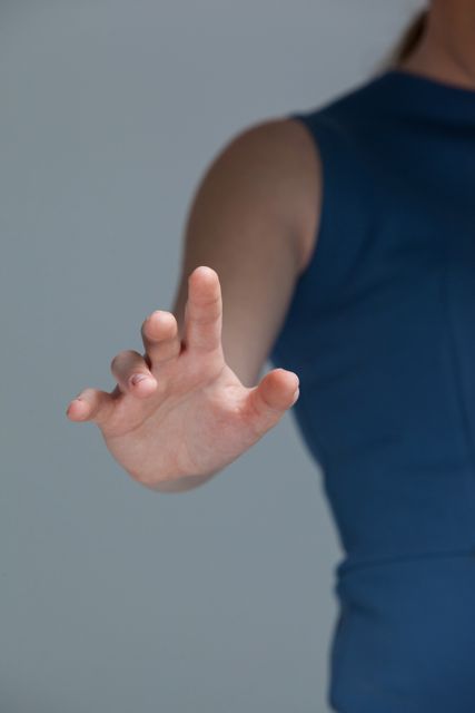 Close-up of hand of a woman touching invisible screen against grey background