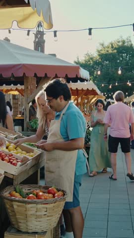 Vendor arranging tomatoes and lemons at busy farmers market during golden hour