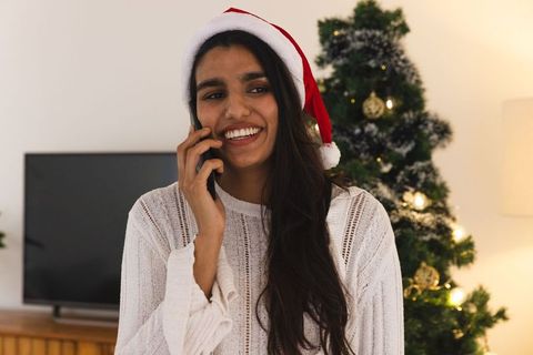 Woman in Santa Hat Talking on Phone by Christmas Tree