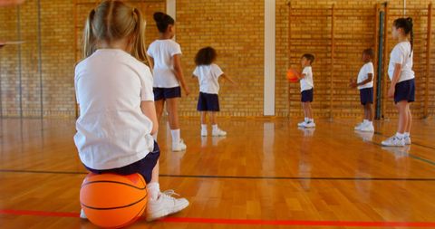 Schoolgirl Sitting on Basketball Watching Kids Practice - Download Free Stock Images Pikwizard.com