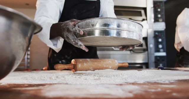 Chef holding baking tray over a floured counter in a professional kitchen. Image illustrates baking preparation, making it perfect for cooking blogs, restaurants, recipe books, and educational materials emphasizing baking techniques.