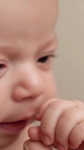 Infant mouthing adult finger, closeup vertical video capturing gentle comforting bonding moment