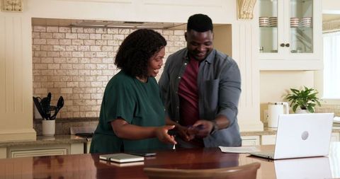 Couple collaborating on finances by kitchen laptop