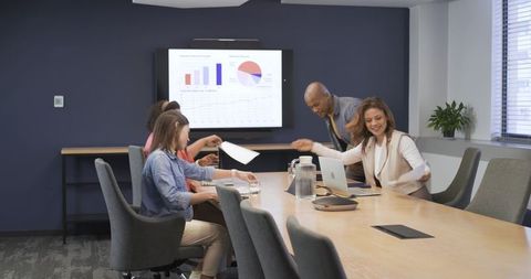 Diverse team presenting and reviewing analytics charts in modern boardroom meeting