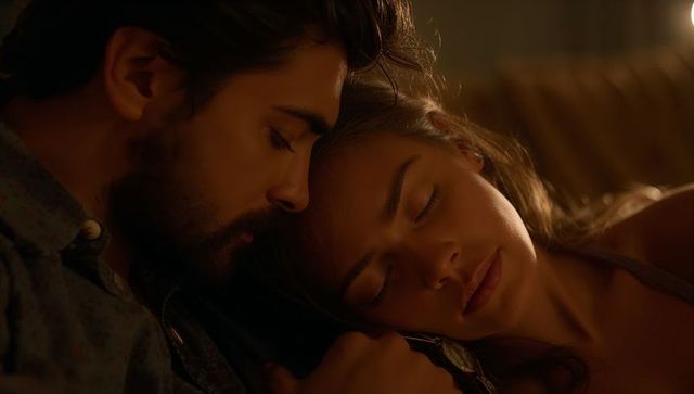 Romantic couple cuddling on sofa under warm lamp light, cozy intimate close-up evening