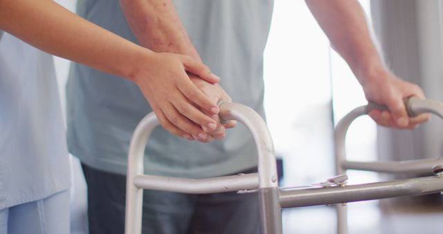 Two hands on a walker, one belongs to an elderly person and the other to a caregiver. This image represents assistance, healthcare, and support. Ideal for use in articles or websites focused on aging, nursing, rehabilitation, assisted living, and healthcare services.