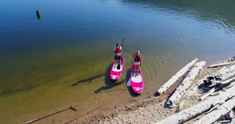 Young adults paddleboarding in serene lake setting