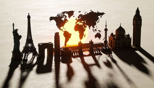 Backlit world landmarks silhouette lineup casting dramatic long shadows with sunlit world map