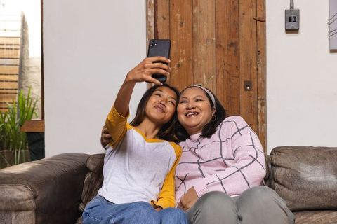Mother and Daughter Taking Selfie on Sofa with Smartphone