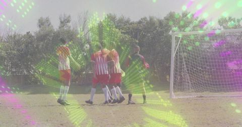 Youth soccer team forming defensive wall at goal with referee and vibrant neon light overlays