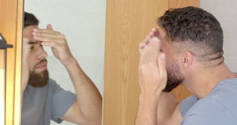 Man Applying Skincare Product in Modern Bathroom Reflection