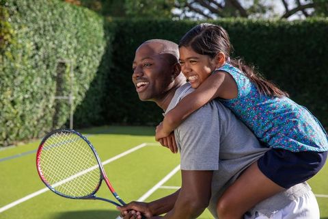 Father and Daughter Playing Tennis Together in Backyard