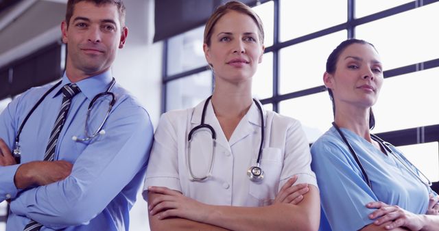 Medical professionals stand confidently with crossed arms in a hospital environment, displaying teamwork and dedication. Suited for articles on healthcare, medical team recruitment, health services promotion, and depicting the importance of professionals in the medical field.