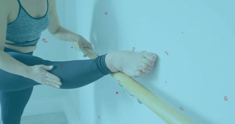 Woman performing leg stretch on ballet barre in dance studio