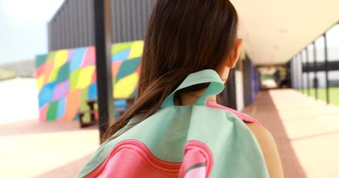 Back to School: Young Girl with Pink Backpack in Sunlit Corridor
