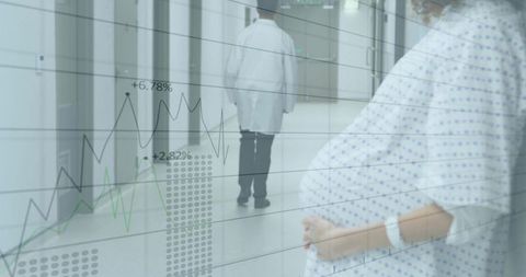 Expectant patient holding bump in hospital corridor with medical data overlay